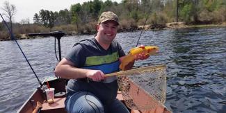 man on boat holding a golden trout