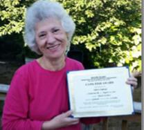 white haired woman holding a certificate