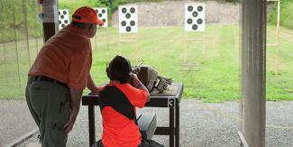 man and youth shooting rifle at gun range