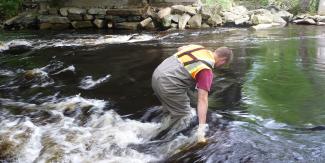 RIDEM staff collecting river water sample