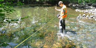 RIDEM staff measure river width and depth to calculate stream flow