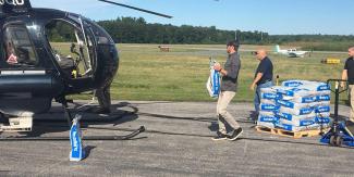 People carrying bags of pellets to a helicopter