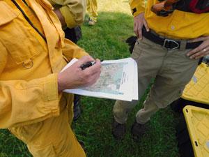 map being held by between people wearing yellow gear