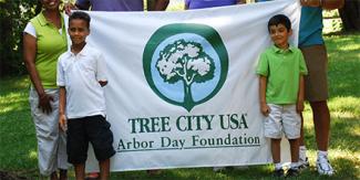 two boys standing in front of a Tree City USA arbor day foundation banner