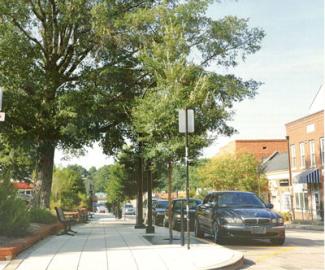 cars parked next to sidewalk lined with trees