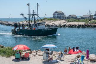 A fishing boat motors past Salty Brine State Beach at the Port of Galilee in Narragansett