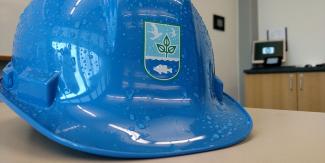 Up close view of a blue hard hat with the DEM logo sitting on a desk