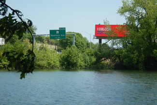 Mashapaug Pond in the foreground with a billboard and highway in the distance next to the waterbody