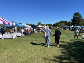 A photos shows people shopping at the RI Grown Farmers Market at Fishermen's Memorial State Park.