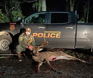 Environmental police officer holding the antlers of a seized deer that was illegally hunted