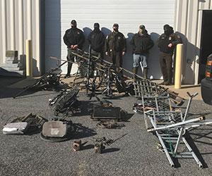 Environmental police officers standing behind seized hunting gear which includes deer stands