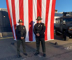 Two environmental police officers standing in front of an American flag in dress uniforms