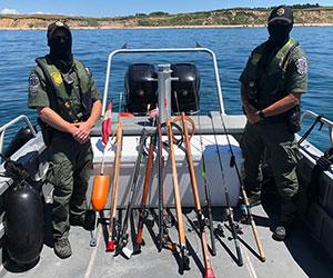 Two environmental police officers stand aboard a vessel with seized fishing gear