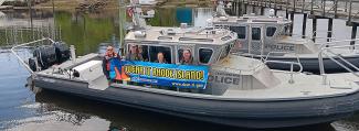RI Law Enforcement vessel with Officers holding a banner saying "Wear It"